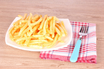 French fries, a plate and fork on a wooden background