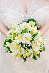 Bride holding beautiful yellow wedding flowers bouquet