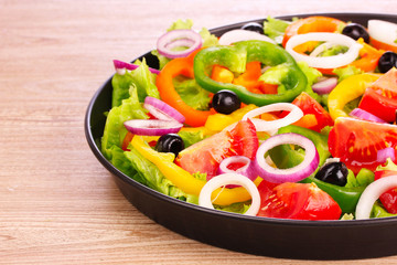 many vegetables in a bowl on wooden background