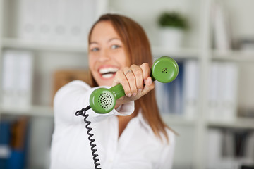 lachende frau zeigt grünes telefon