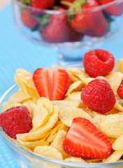 Cornflakes in bowl with berries on a blue background