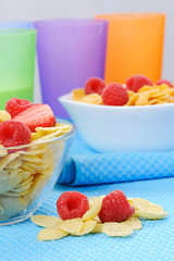 Cornflakes in two bowls with berries and colorful plastic cups