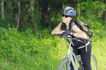 Fototapeta na wymiar young biker woman getting rest in forest area