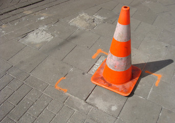 orange traffic cone on gray stone pavement tiles
