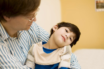 Father holding disabled son in doctor's office