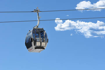 Gondelbahn vor blauem Himmel mit Wolken