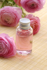 Obraz na płótnie Canvas perfume bottles and ranunculus flowers and on woven mat