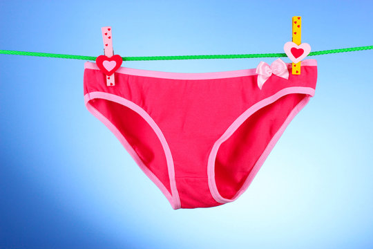 Woman's panties hanging on blue background