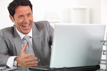 Man laughing hysterically at his laptop computer