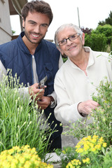 Young man and elderly woman gardening