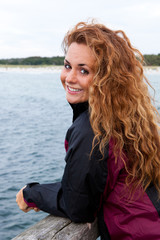 Fototapeta na wymiar junge Frau in Windjacke auf einer Seebrücke