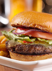gourmet cheeseburger with mug of beer in background