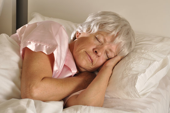 Seniorin schl&auml;ft in einem Bett