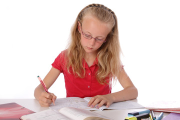 fillette blonde de 9 ans avec lunettes faisant ses devoirs