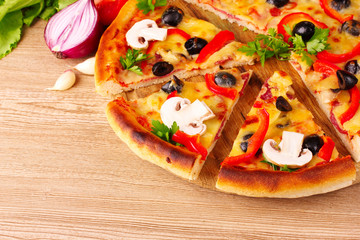 pizza and vegetables on wooden background