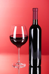Wine bottle and glass on red background