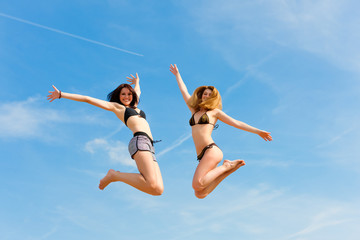 Two happy women jumping high with fun