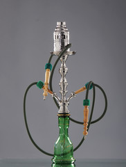 An old green Arabic hookah on a grey background
