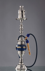An old silver Arabic hookah on a grey background