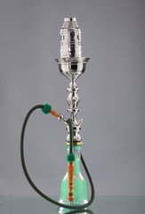 An old green Arabic hookah on a grey background