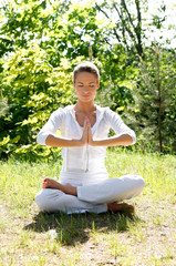 A young and attractive woman is meditating in a forest