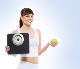 A young brunette with measuring scales and an apple