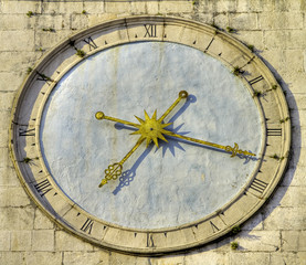 Ancient clock with roman numbers and golden hands.