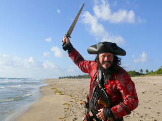 Pirate in vintage costume on the beach with sword
