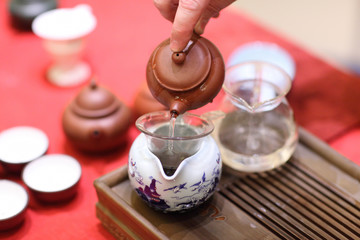 Man pours tea into faircup from teapot