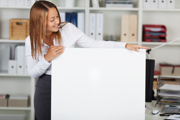 junge frau im büro schaut auf weißes schild