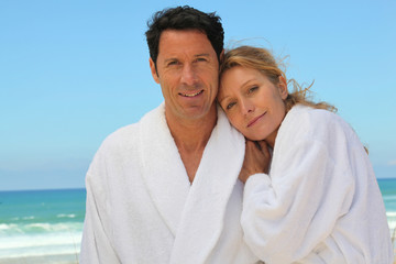 Obraz premium Attractive couple in bathrobes on the beach