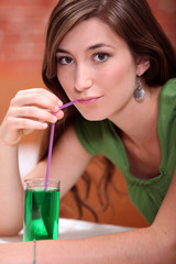 young woman dressed in green drinking a lemonade