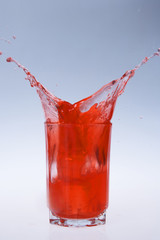 red fruity juice water splash coming out of a glass