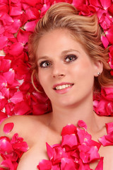 Obraz na płótnie Canvas Attractive blond girl portrait in roses petals.