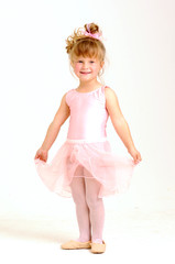 Little smiley girl wearing a pink ballet outfit is dancing