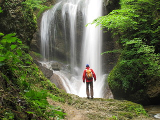 Wanderer steht vor Wasserfallstufe