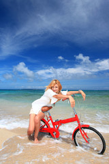 Fototapeta na wymiar ビーチで自転車に乗る笑顔の女性
