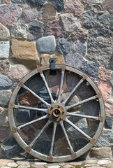 Fototapeta na wymiar Old wooden wheel is placed near wall