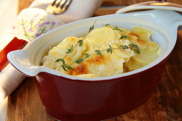 Potato gratin dauphinoise in the pan on rustic background