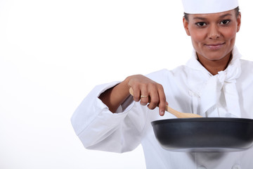 female cook with a high-sided frying pan and a wooden spoon