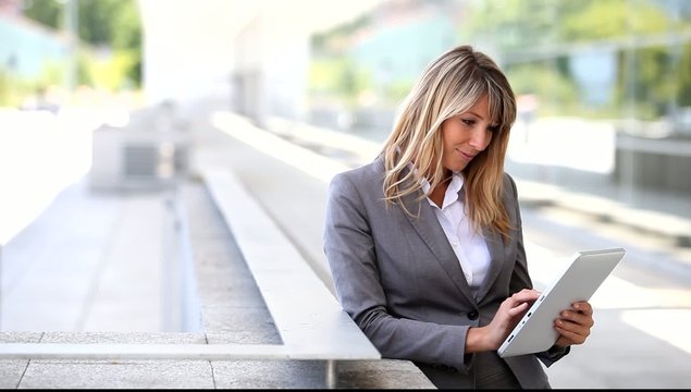Businesswoman using electronic tablet outside building