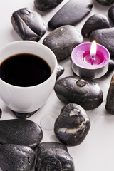Tazzina di caffè su sassi di fiume e candela