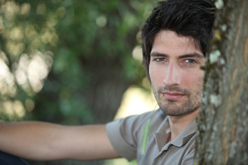 Closeup of a handsome young man sitting amongst the trees