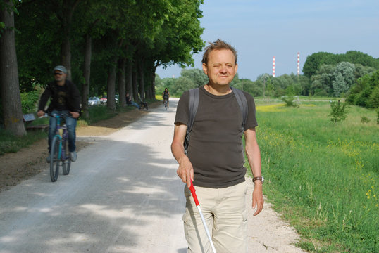Blinder Mann mit Langstock unterwegs im Freien