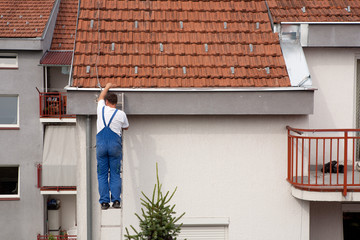 Man on a ladder climbing on the roof