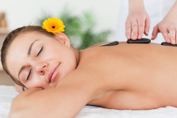 Obraz na płótnie Canvas Delighted woman having a hot stone massage