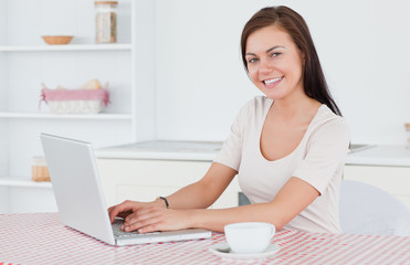 Brunette using her laptop and having a tea