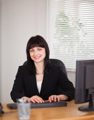 Good looking brunette woman working on a computer while sitting