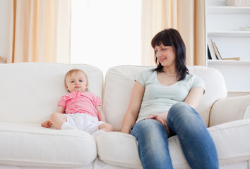 Pretty woman looking at her baby while sitting on a sofa