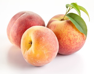 Three ripe peach with leaves